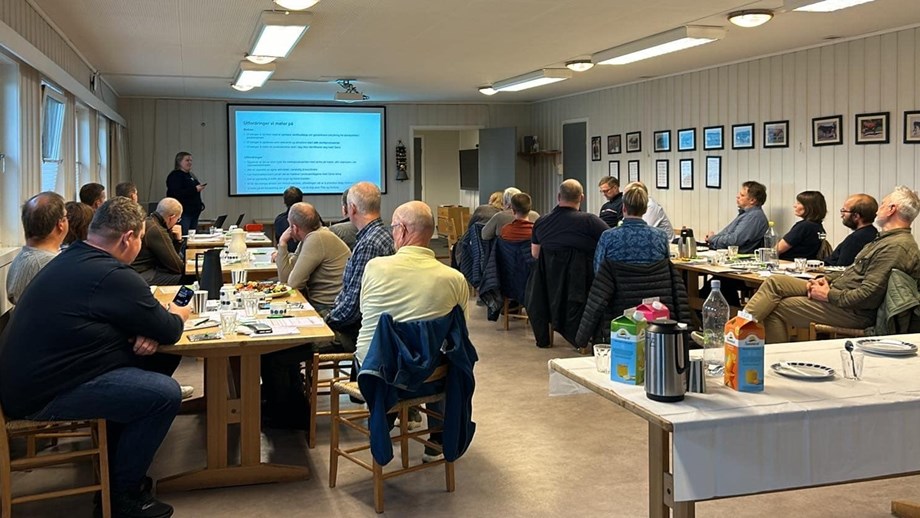 Deltakerne som sitter rundt bord og ser fremover mot en skjerm og Agnete Børresen som foran på høstmøtet fotografert bakfra.