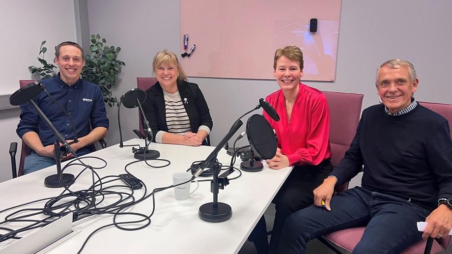 Gjester og programledere sitter rundt et bord i studio og smiler mot kamera.